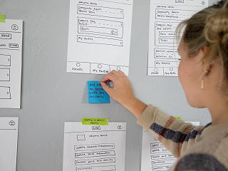 Employee Adding notes to large idea board